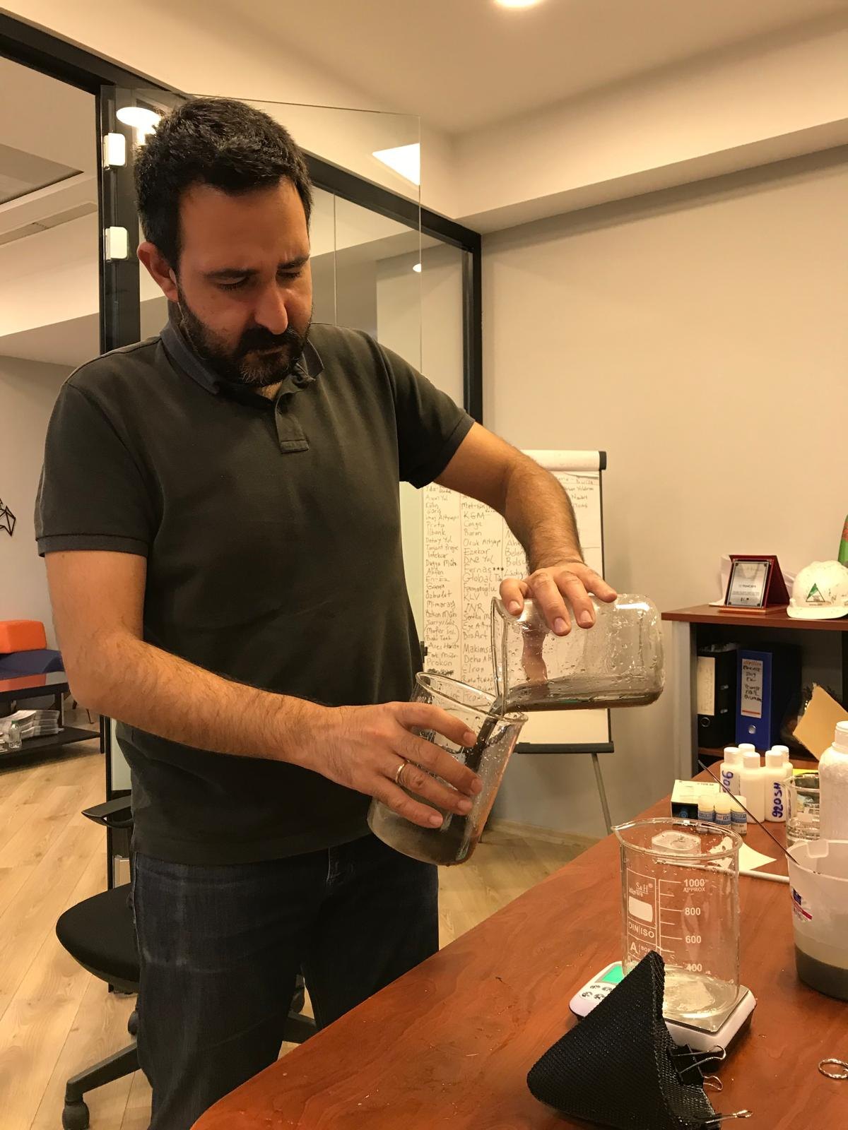 Bir çalışanın masa üzerinde geotekstil filtreyle yaptığı numune testi.